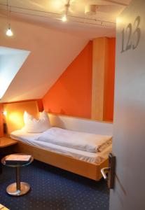 Bett in einem Zimmer mit orangefarbener Wand in der Unterkunft Hotel Bergwirt in Herrieden