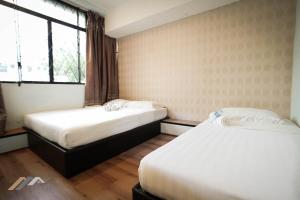 two beds in a hotel room with a window at Welcome Inn by Evernent @ Pelita Commercial, Miri in Miri