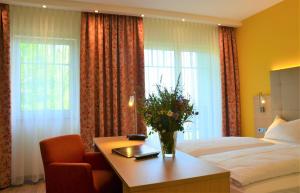 pokój hotelowy z łóżkiem i stołem z kwiatami w obiekcie Hotel Bergwirt w mieście Herrieden