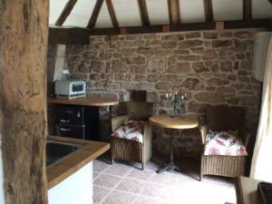 cocina con mesa y sillas en una pared de piedra en Countryside tiny house near Chateau de Hautefort, en Boisseuilh