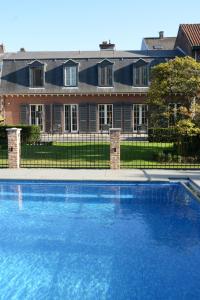 une grande piscine bleue en face d'une maison dans l'établissement Notarishuis Beveren B&B, à Beveren