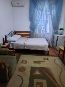 a bedroom with a bed and a couch and a rug at Hotel ВаYan in Shymkent