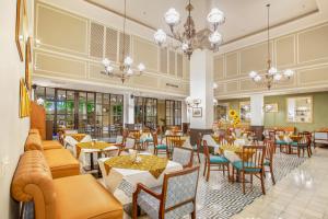 ein Restaurant mit Tischen, Stühlen und Kronleuchtern in der Unterkunft Hotel Des Indes Menteng in Jakarta