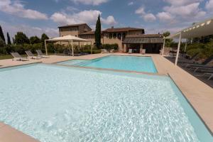 une grande piscine avec des chaises et une maison dans l'établissement Resort Casale Le Torri, à Ponsacco