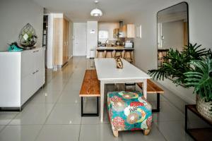 a living room with a table and a kitchen at Plett Holiday Apartment in Plettenberg Bay