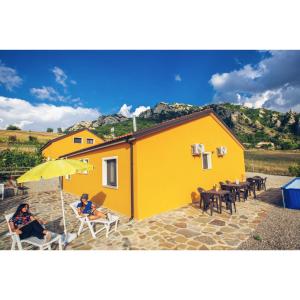 two people sitting under an umbrella in front of a yellow house at Spazio Natura in Castelmezzano