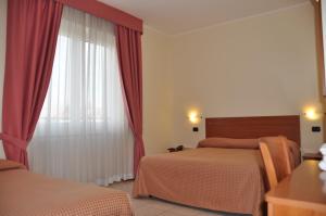 a bedroom with two beds and a window with red curtains at Hotel Belforte in Varese