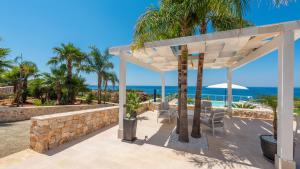 a patio with palm trees and the ocean at Tenuta Scialandre 10, Emma Villas in Patù