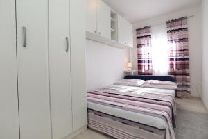 a bedroom with a bed with white cabinets at Apartment Meri in Trogir