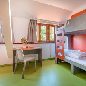 Schlafzimmer mit einem Schreibtisch und einem Etagenbett in der Unterkunft DJH Jugendherberge Torgau in Torgau