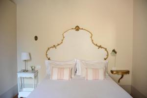 a bedroom with a bed with a gold headboard and pillows at 1550 Residenza d’Epoca in Siena