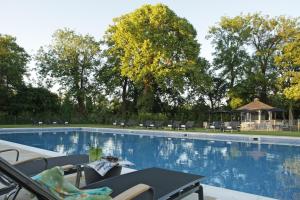 a large swimming pool with chairs and a gazebo at The Runnymede on Thames in Egham