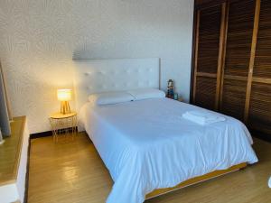 マシコにあるFlats Lago 19のベッドルーム(ランプ付きの白い大型ベッド1台付)