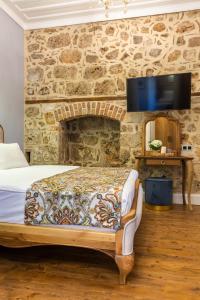 a bedroom with a bed and a tv on a stone wall at Hotel Lykia Old Town Antalya in Antalya