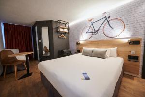 ein Hotelzimmer mit einem Bett und einem Fahrrad an der Wand in der Unterkunft Kyriad Hotel Laval in Laval + 69 Fotos