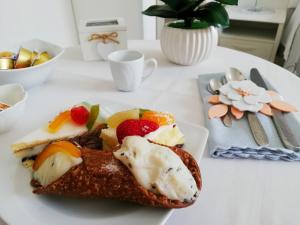 a white plate with a sandwich and fruit on a table at B&B PLAZA in Lampedusa
