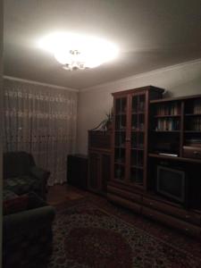 een woonkamer met een bank en een boekenplank bij Prima in Loetsk