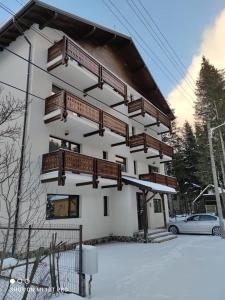 een gebouw met houten balkons in de sneeuw bij Anastasia apartments in Buşteni