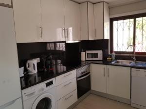 a kitchen with white cabinets and a washing machine in it at Forte Beach- Albufeira in Albufeira