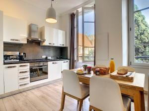 une cuisine avec des placards blancs et une table et des chaises en bois dans l'établissement Nestor&Jeeves - COTE JARDIN - Central - Close sea, à Nice