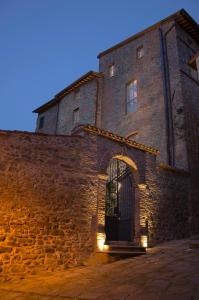 un antiguo edificio de piedra con una puerta y luces en Antico Sipario Boutique Hotel, en Paciano