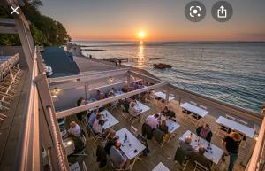 a group of people sitting at tables watching the sunset at Bay - Brambles Chine, Colwell Bay - 5 star WiFi - Short walk to The Hut and beach - 1 night stays available - Ferry offers in Freshwater