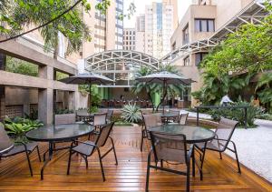 un patio con mesas, sillas y sombrillas en Estanplaza International en São Paulo