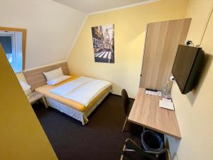 a small room with a bed and a television at Hotel Residenz Stockstadt in Stockstadt am Main