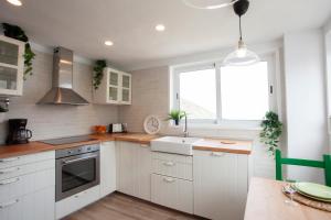 eine Küche mit weißen Schränken und einer Spüle und einem Fenster in der Unterkunft Casa campo y Playa Taganana in Taganana