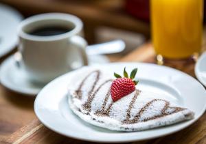 a plate with a strawberry on a table with a cup of coffee at Estanplaza International in Sao Paulo +49 photos