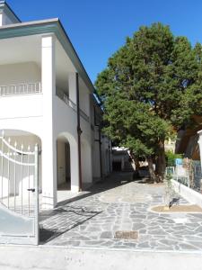 um edifício branco com uma árvore ao lado em CASE I GINEPRI A/B E ATTICO em Cala Gonone