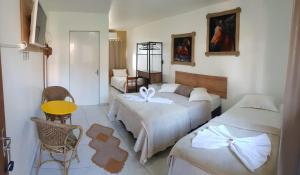 Un dormitorio con dos camas y una mesa y una silla. en Pousada Alegria do Cowboy, en Penha