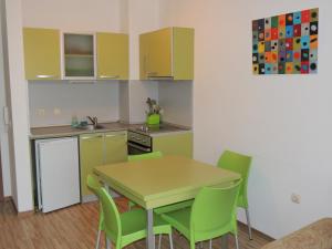 a small kitchen with a table and green chairs at Apartments in Relax Complex Fantasy in Hisarya