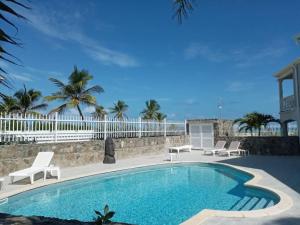 una piscina con sillas y una valla blanca en Princess Coco, Beachfront, Pool, Orient Bay, ultra fast Wifi, en Orient Bay