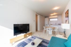 ein Wohnzimmer mit einem Sofa, einem TV und einem Tisch in der Unterkunft Barreirinha Front-Line Sea View I by HR Madeira in Funchal