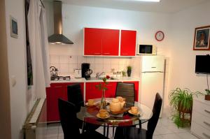 eine Küche mit roten Schränken und einem Tisch mit Stühlen in der Unterkunft Apartment Rosa 1 (AP-A4) in Rovinj