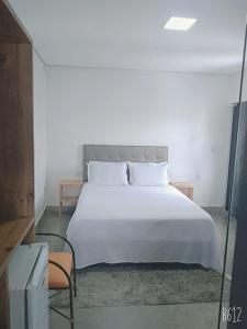 a bedroom with a large white bed and a chair at Villa Maria in Capitólio