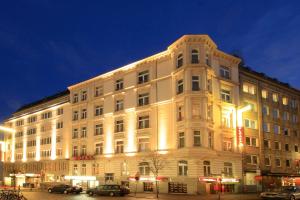 a large white building at night with cars parked in front at Novum Hotel Eleazar City Center in Hamburg