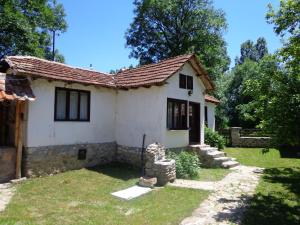 a small white house with a roof at Etno kuca Nikolov in Dimitrovgrad