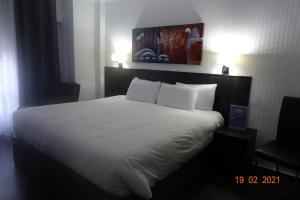 a bed with white sheets and pillows in a hotel room at Hotel Carlos III in Águilas