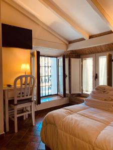 a bedroom with a bed and a desk and windows at Hotel Plaza Grande in Zafra
