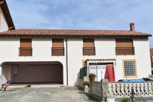 a white house with a garage at Precioso apartamento reformado en Liencres in Liencres