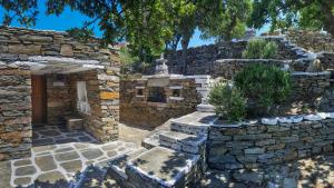una antigua casa de piedra con una pared de piedra y un patio en Under Royal Oaks, en Péra Meriá