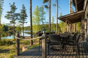 a deck with a table and chairs and a view of a lake at Beautiful lakeside Villa Vetojärvi in Pennala