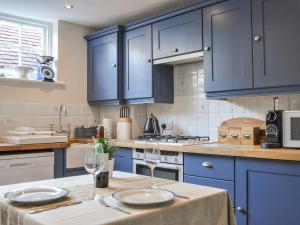 a kitchen with blue cabinets and a table with two wine glasses at Starboard Light in Lymington