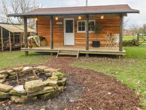 a log cabin with a stone wall in front of it at Bramley Orchard Glamping in Retford