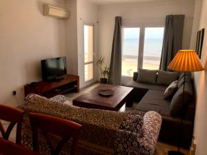 een woonkamer met een bank, een tafel en een televisie bij GATU PREMIUM Vista Infinita 1ªlinea mar WIFI, AIRE ACC in Cádiz
