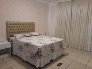 a bedroom with a bed with a floral bedspread at Casa da Adriana Pousada in Fortaleza