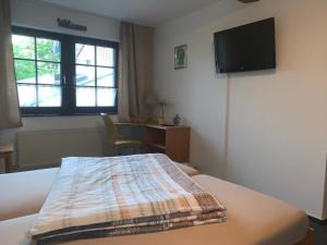ein Hotelzimmer mit einem Bett und einem Flachbild-TV in der Unterkunft Hotel am Neumarkt in Zeitz