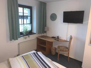 a bedroom with a desk and a bed and a television at Hotel am Neumarkt in Zeitz